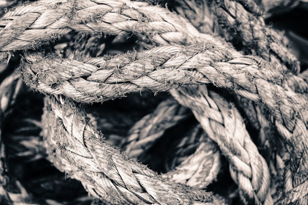 This image contains a knot in black and white. The knot is meant to represent the complexity of imposter syndrome’s many interconnected causes.