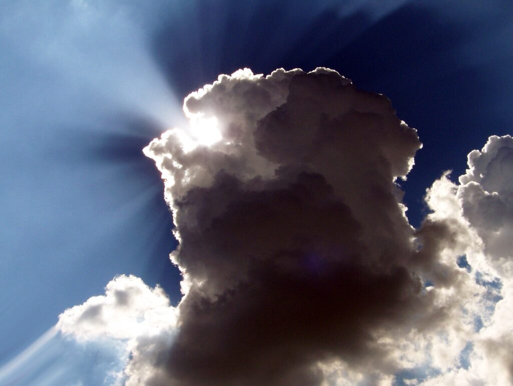 This image contains a dark cloud against a blue sky. The edges of the cloud are lit up by the sun’s rays. The picture symbolizes the metaphor ‘Every cloud has a silver lining’.